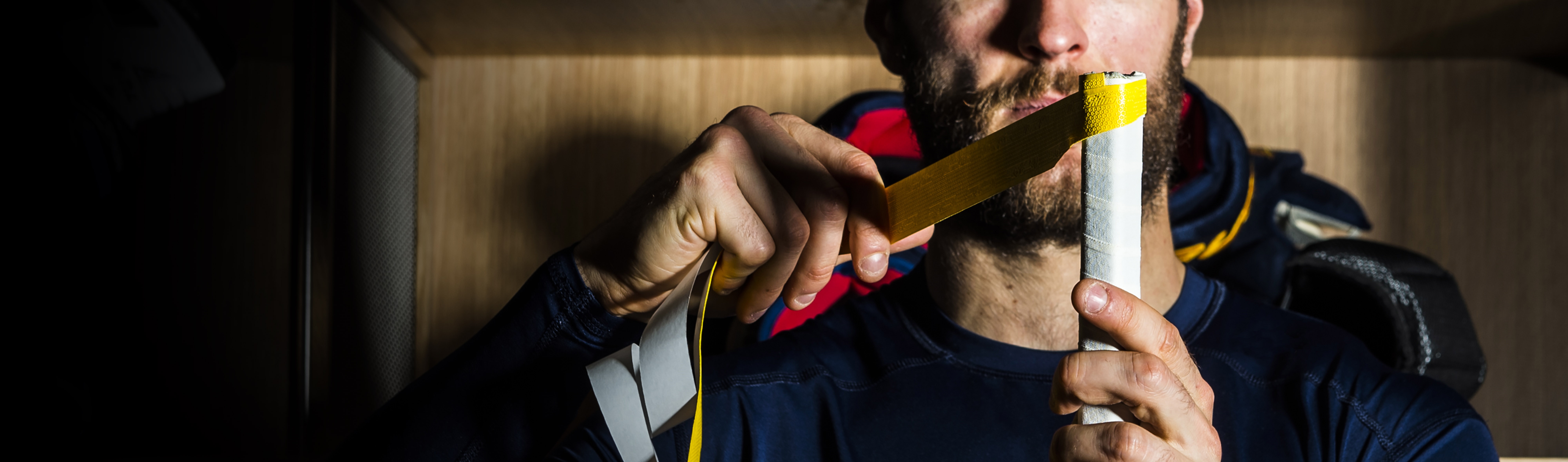 Man wrapping a hockey stick with grip tape